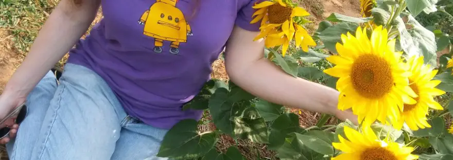 redhaired lady in sunflower field with text overlay: the organic eczema spray that changed everything for me